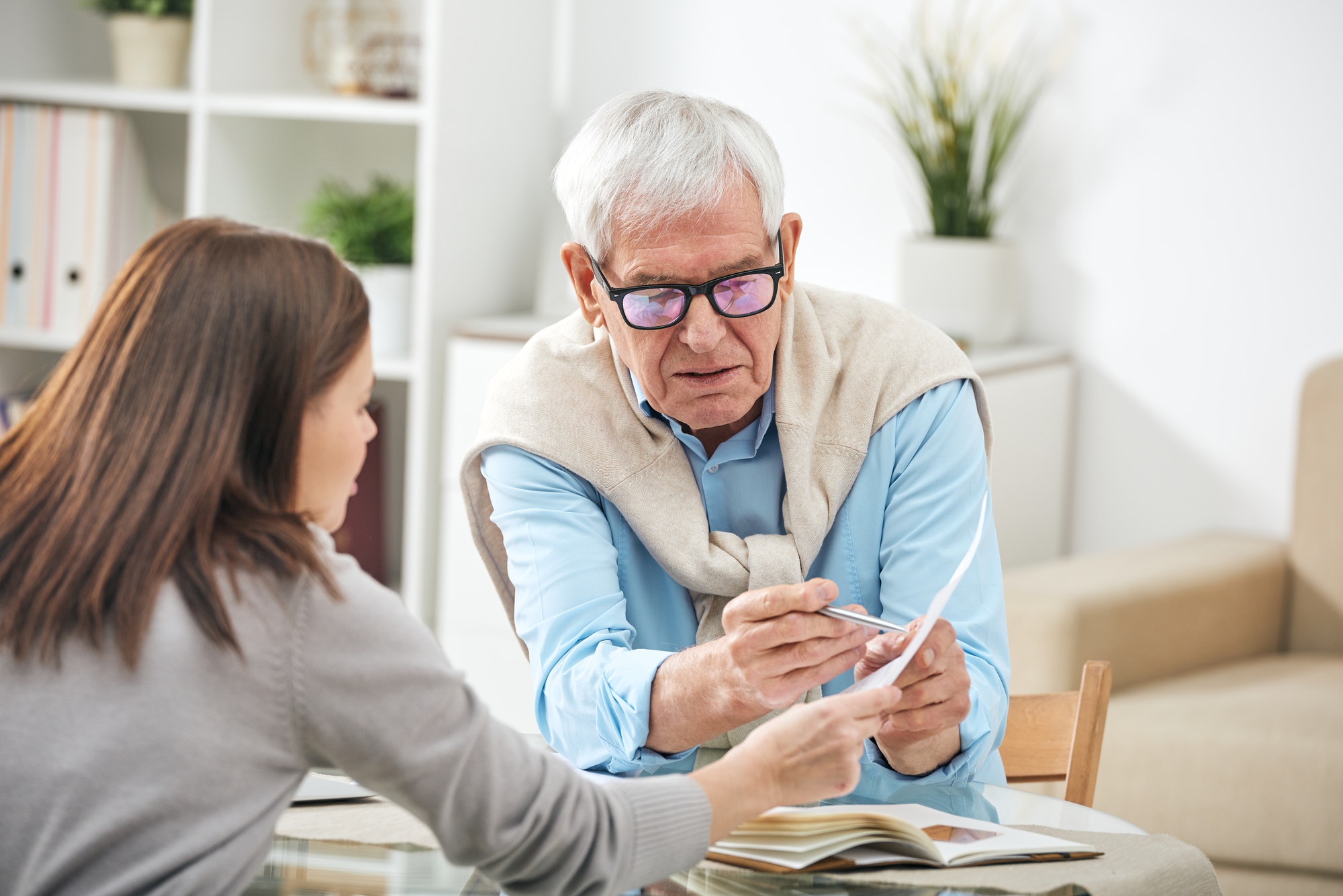 young social worker or insurance agent asking questions of senior man
